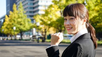 振り向きながらささやかにガッツポーズをし、小さな自信をうかがわせるスーツ姿の女性